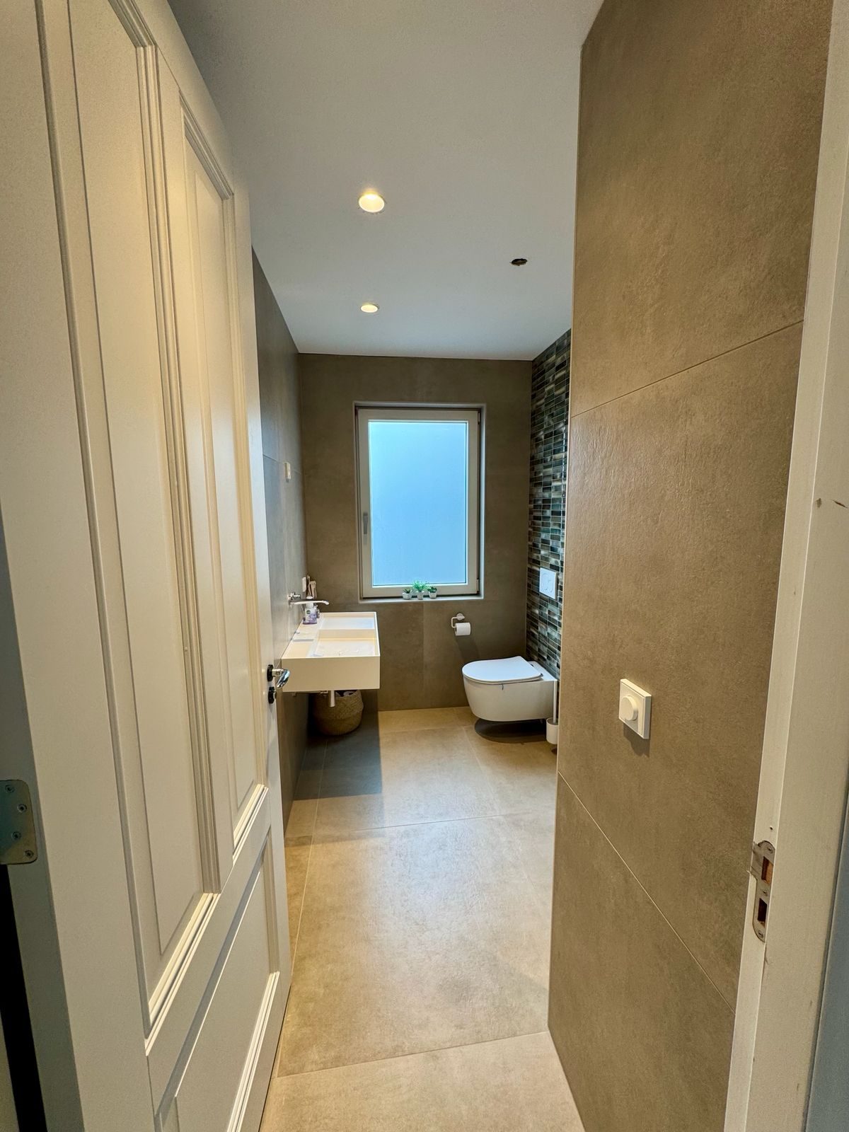 Gerenoveerde badkamer met strak tegelwerk en zwevend toilet